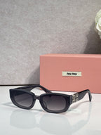 MiuMiu sunglasses with black frames and dark lenses, cat-eye silhouette
