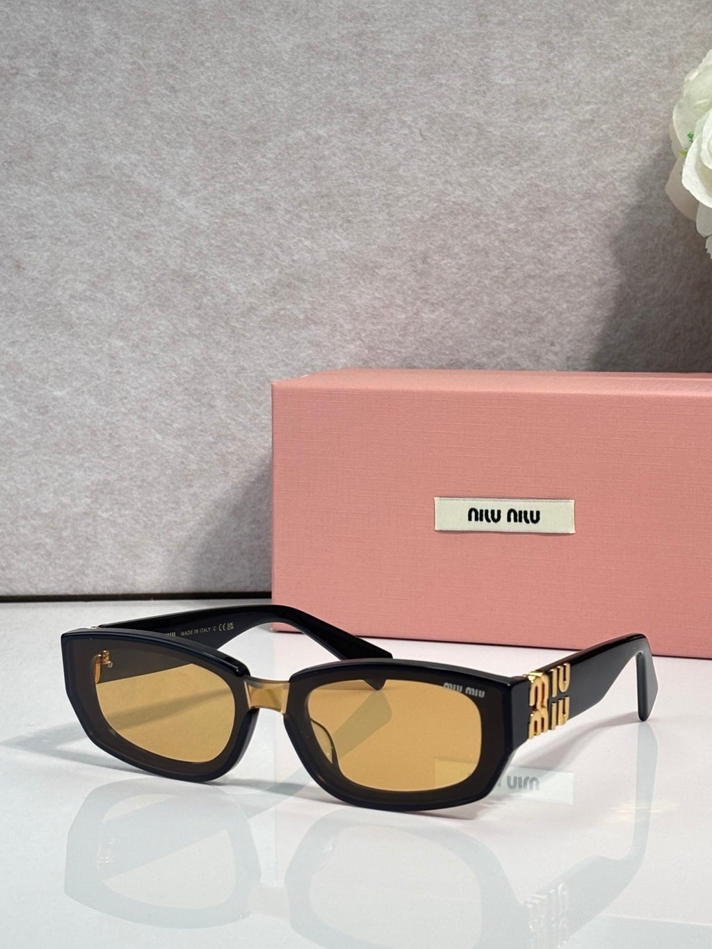 MiuMiu sunglasses with dark frames and amber-brown tinted cat-eye lenses