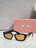 MiuMiu sunglasses with dark frames and amber-brown tinted cat-eye lenses