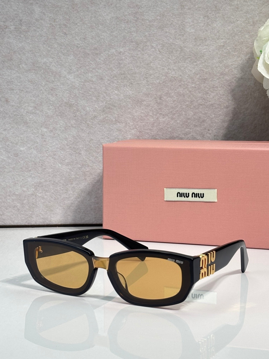 MiuMiu sunglasses with dark frames and amber-brown tinted cat-eye lenses
