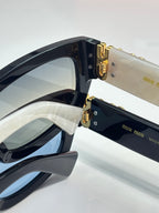 MiuMiu sunglasses close-up with gold-tone hinge hardware and dark lenses