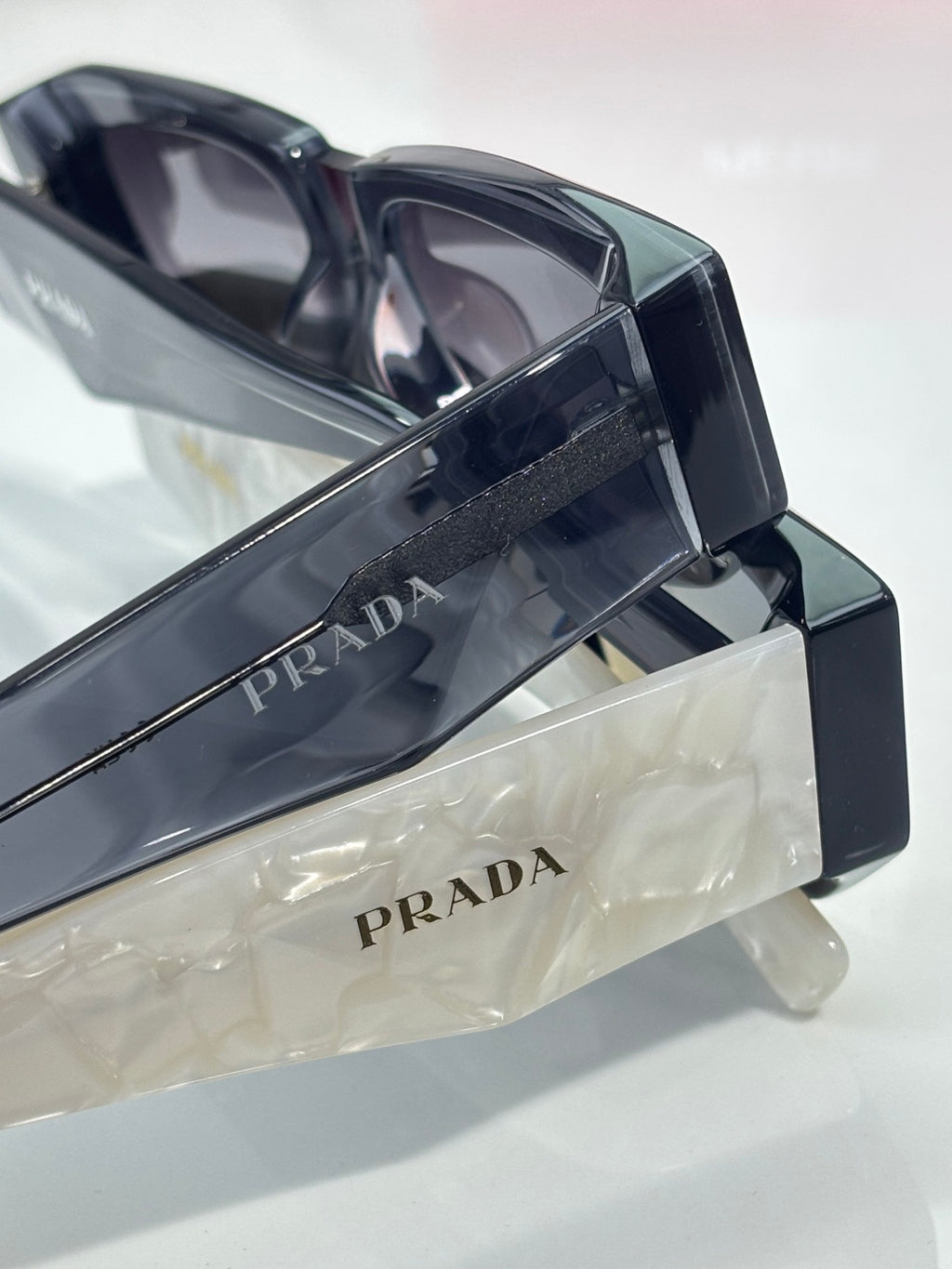 Prada glasses temple arm close-up with PRADA engraving and hinge detail
