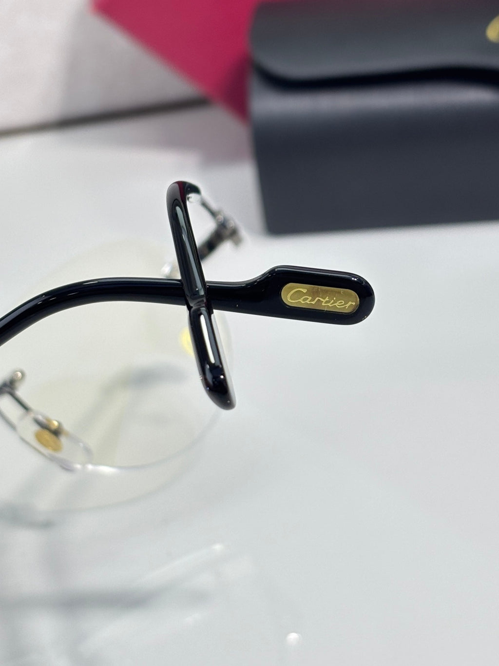Black eyeglass temple with gold oval logo and clear front frame