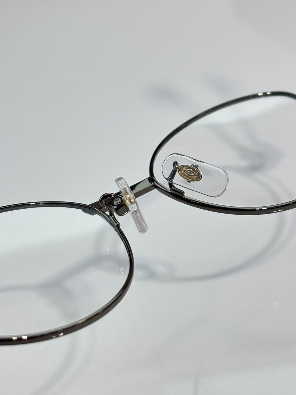 Cartier eyeglasses close-up, round clear lens with black frame and gold logo plate