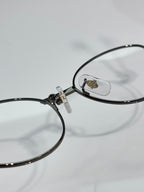 Cartier eyeglasses close-up, round clear lens with black frame and gold logo plate