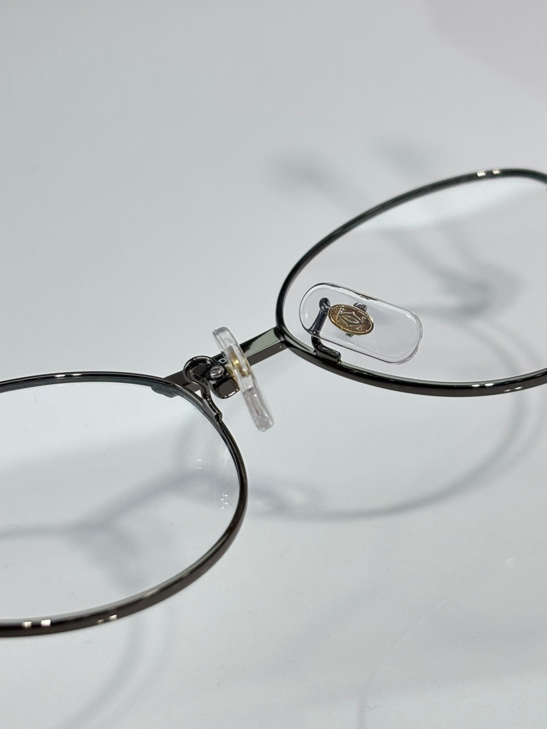 Cartier eyeglasses close-up, round clear lens with black frame and gold logo plate