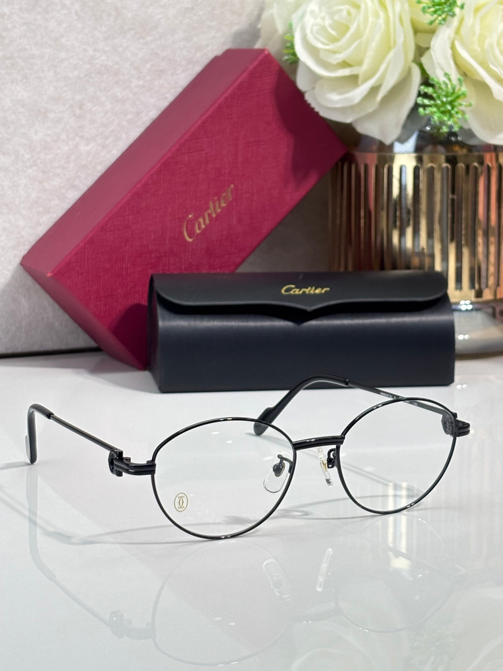 Cartier eyeglasses, round clear lenses, black metal frame with gold logo accents