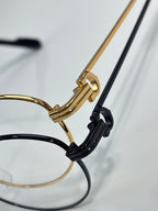 Cartier eyeglasses temple detail, gold arm with black hinge and clear lens