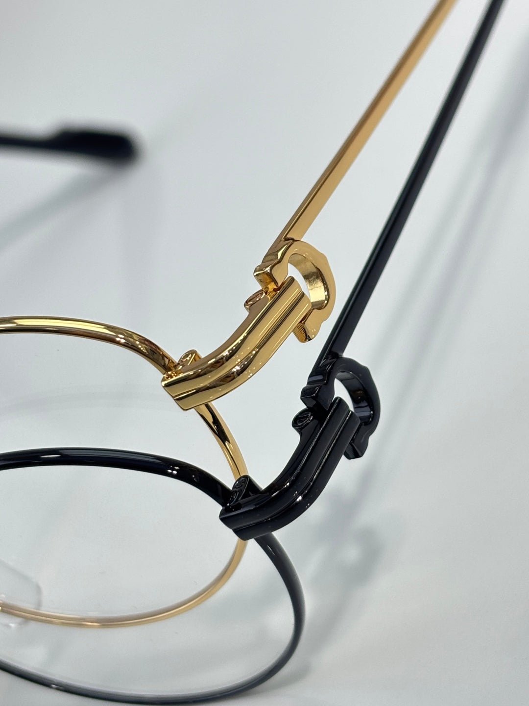 Cartier eyeglasses temple detail, gold arm with black hinge and clear lens