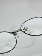 Round metal eyeglasses close-up at nose bridge and temple hinge