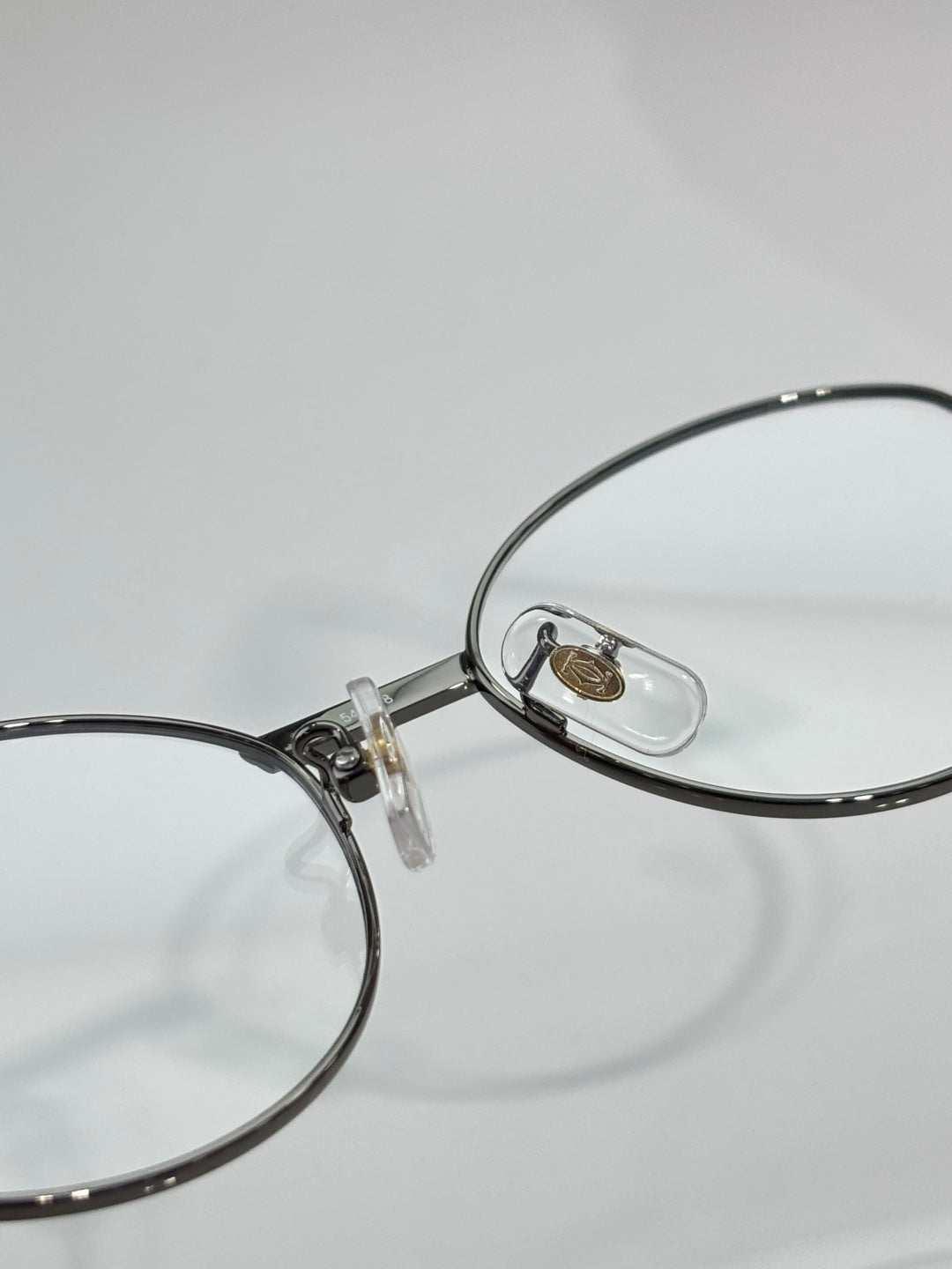 Round metal eyeglasses close-up at nose bridge and temple hinge