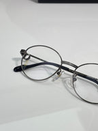 Round metal eyeglasses angled view showing clear lenses and black temple arms