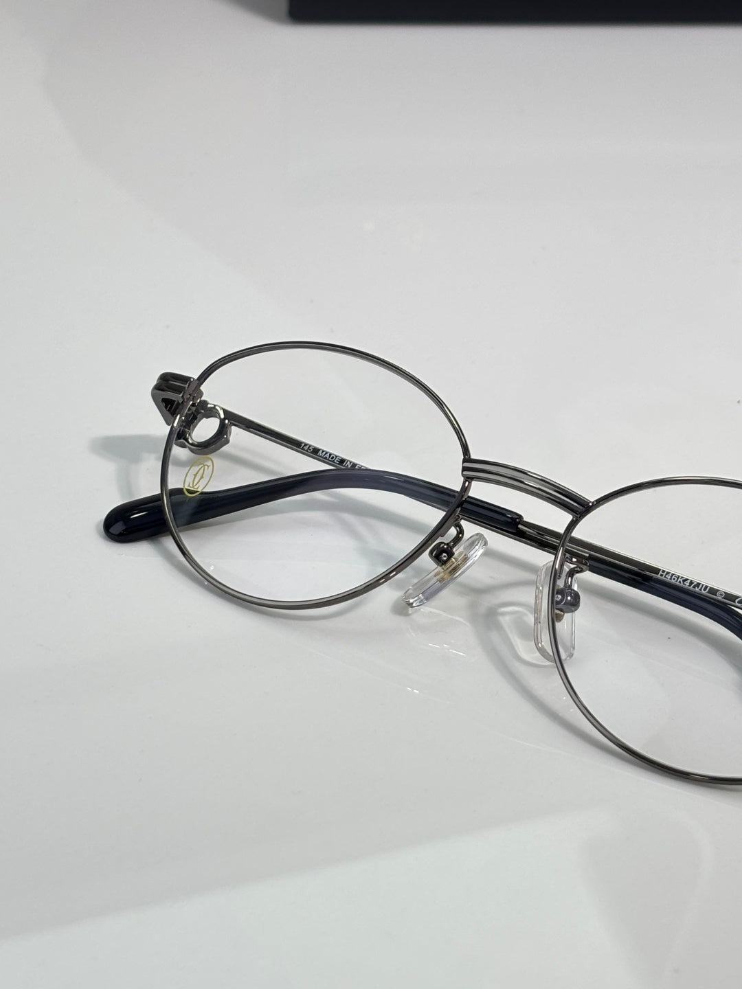 Round metal eyeglasses angled view showing clear lenses and black temple arms