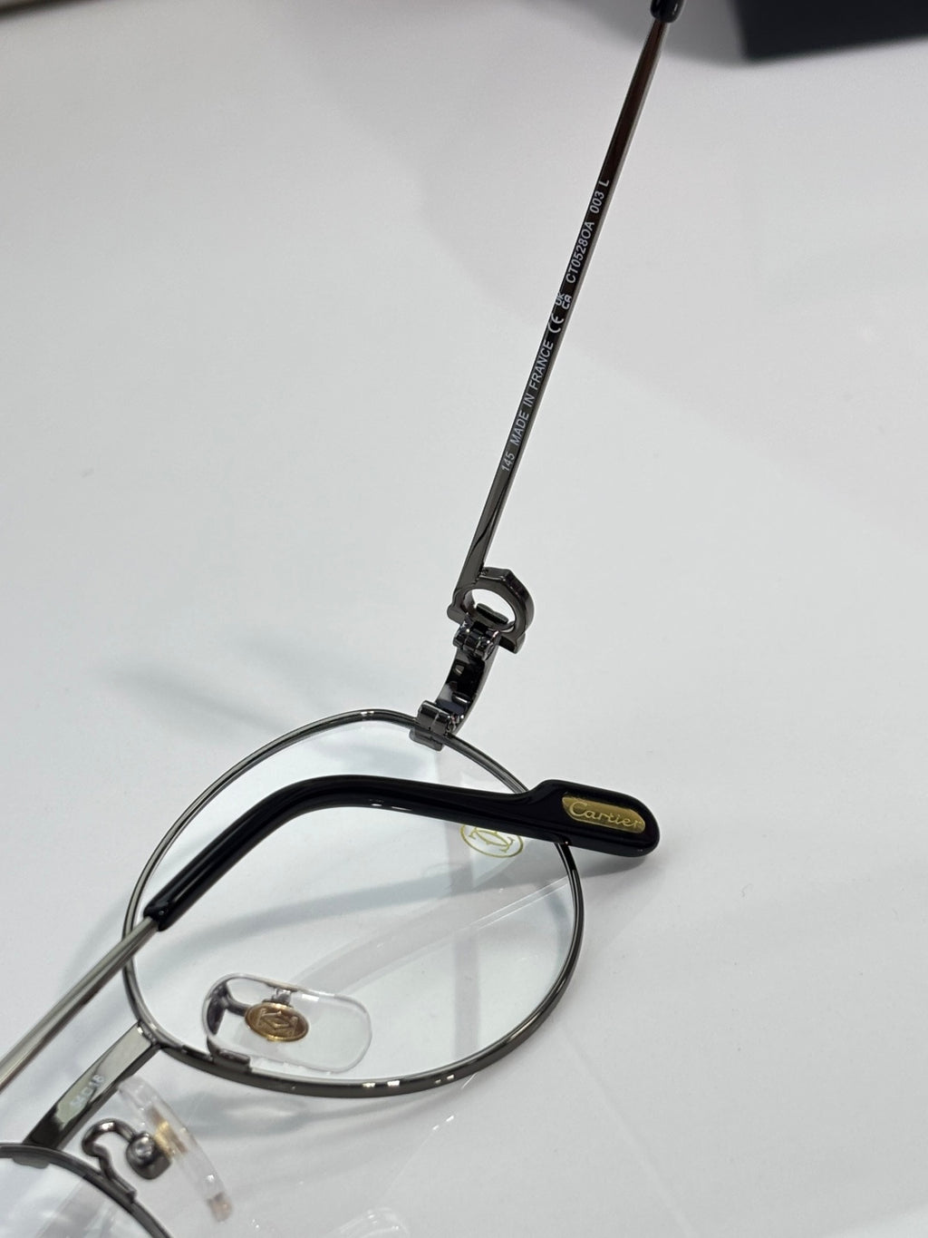 Round metal eyeglasses side view with black temple arm and printed logo strip