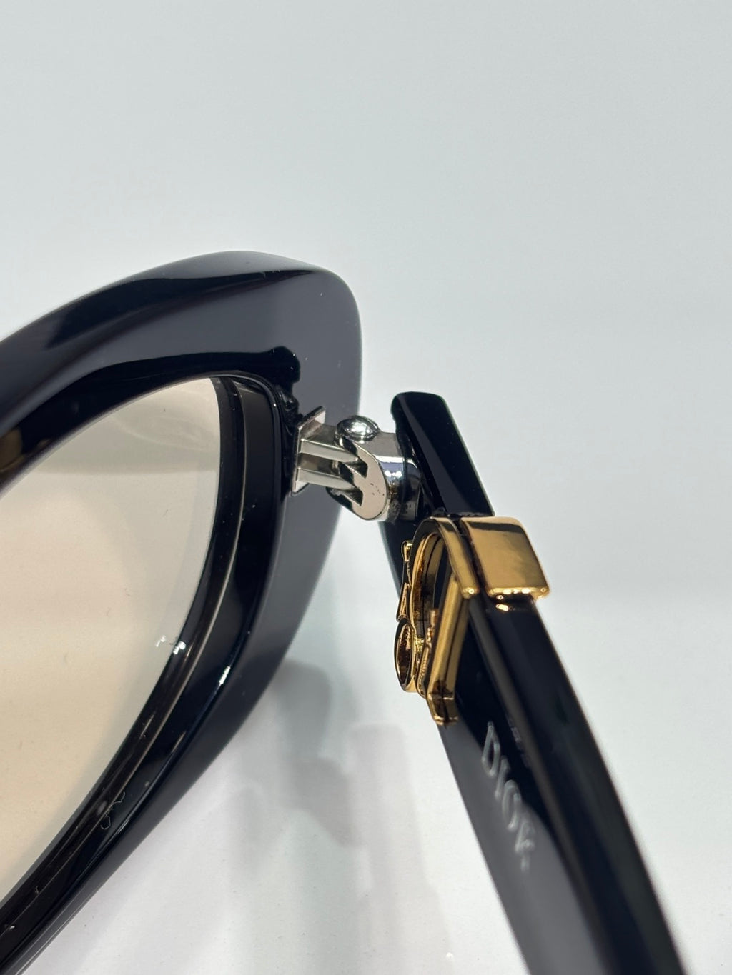 Dior sunglasses close-up: gold-tone hinge on dark frames
