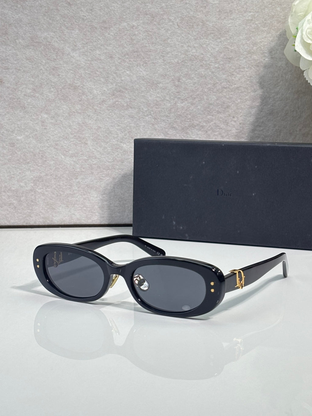Dior black oval sunglasses with dark gray lenses and gold-tone emblem