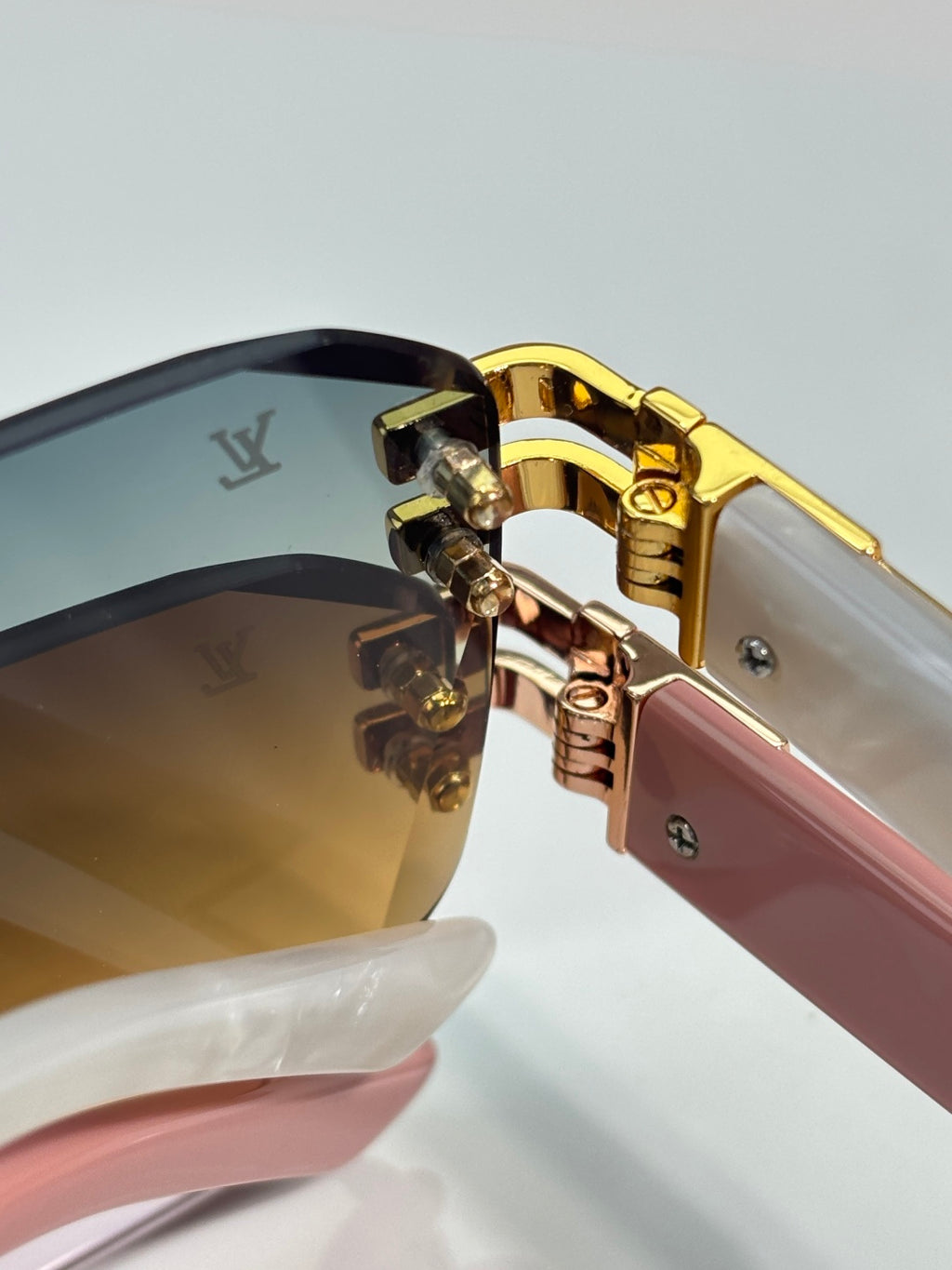 Louis Vuitton glasses close-up of gold hinge and pink temple with dark gradient lenses