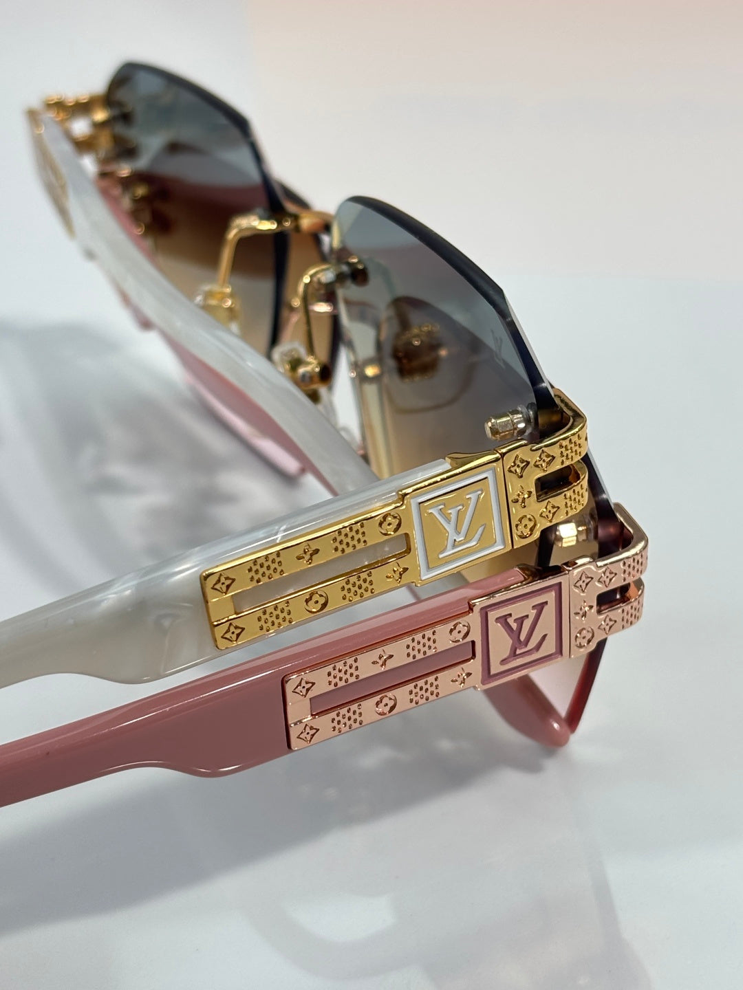 Louis Vuitton glasses close-up with pink temples, gold LV bar, and gradient dark lenses