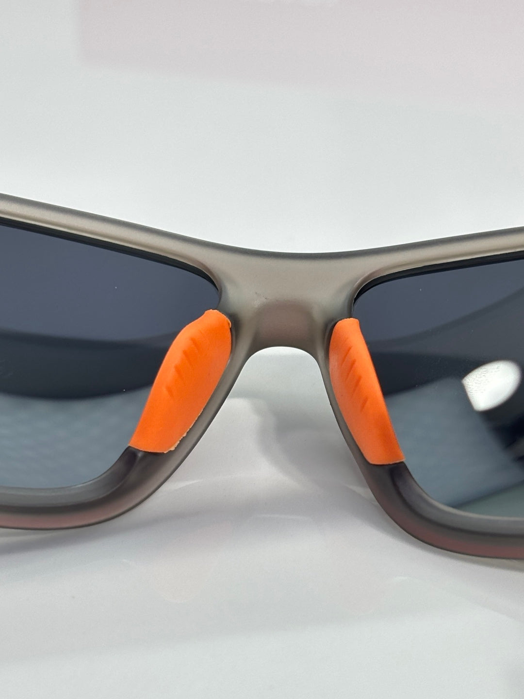 Prada sunglasses with gray frame and orange temple tips, close-up of front