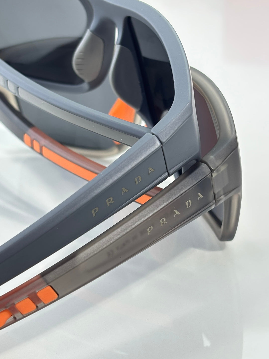 Prada sunglasses side view with gray temple and orange logo stripe