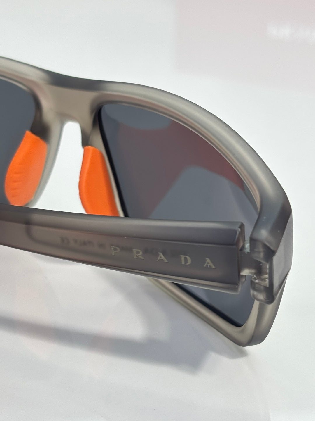 Prada sunglasses close-up of side frame, orange temple tips and logo bar