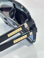 Prada glasses temple close-up with gold Prada lettering and metal hinge