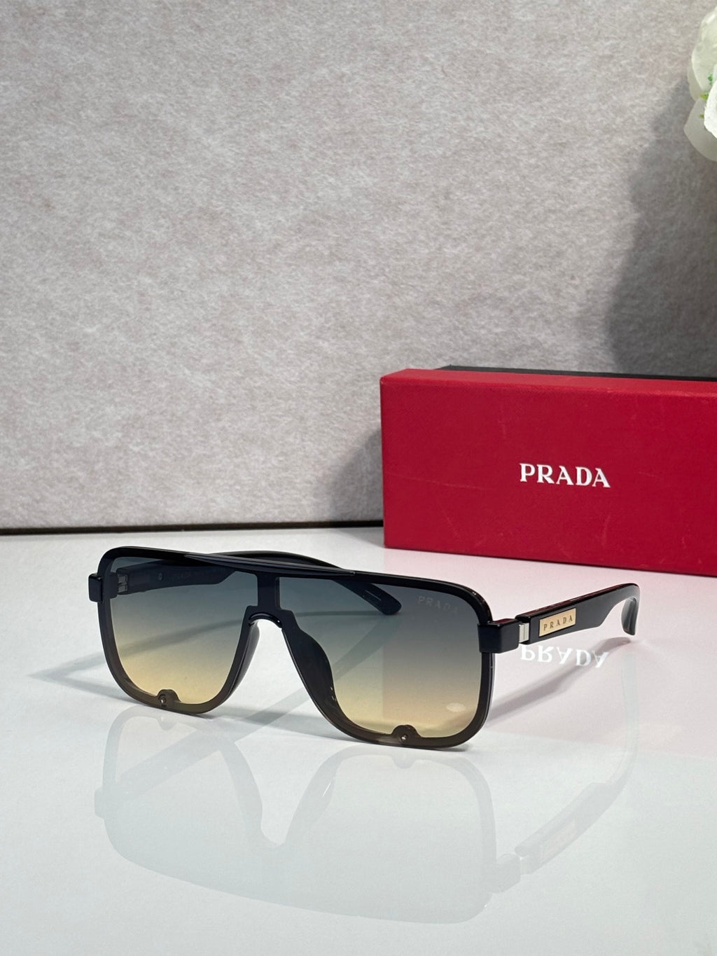 Prada black rectangular sunglasses with gradient lenses and gold logo on temple