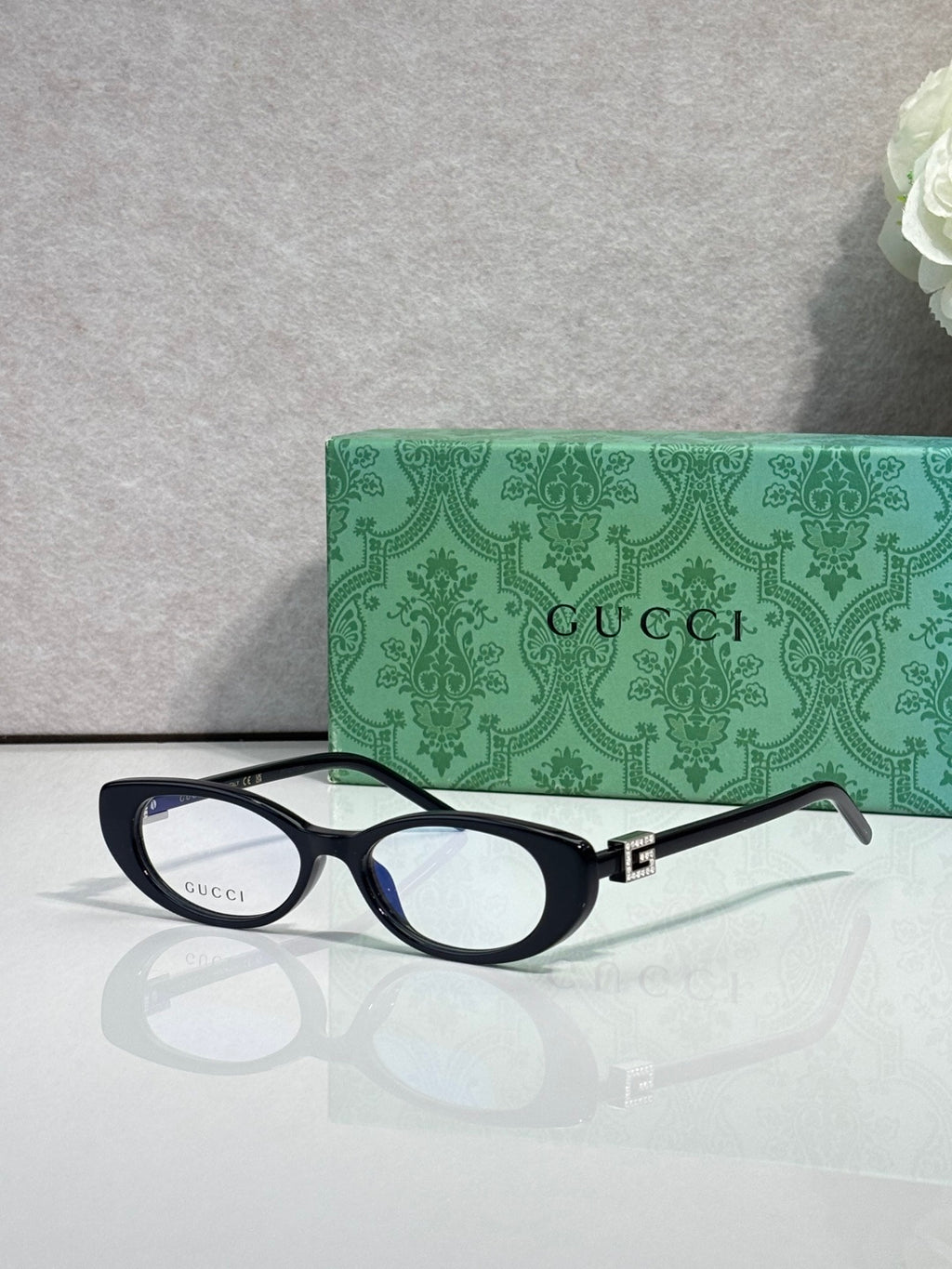 Cat-eye sunglasses with dark frames and clear lenses, gold logo hinge detail
