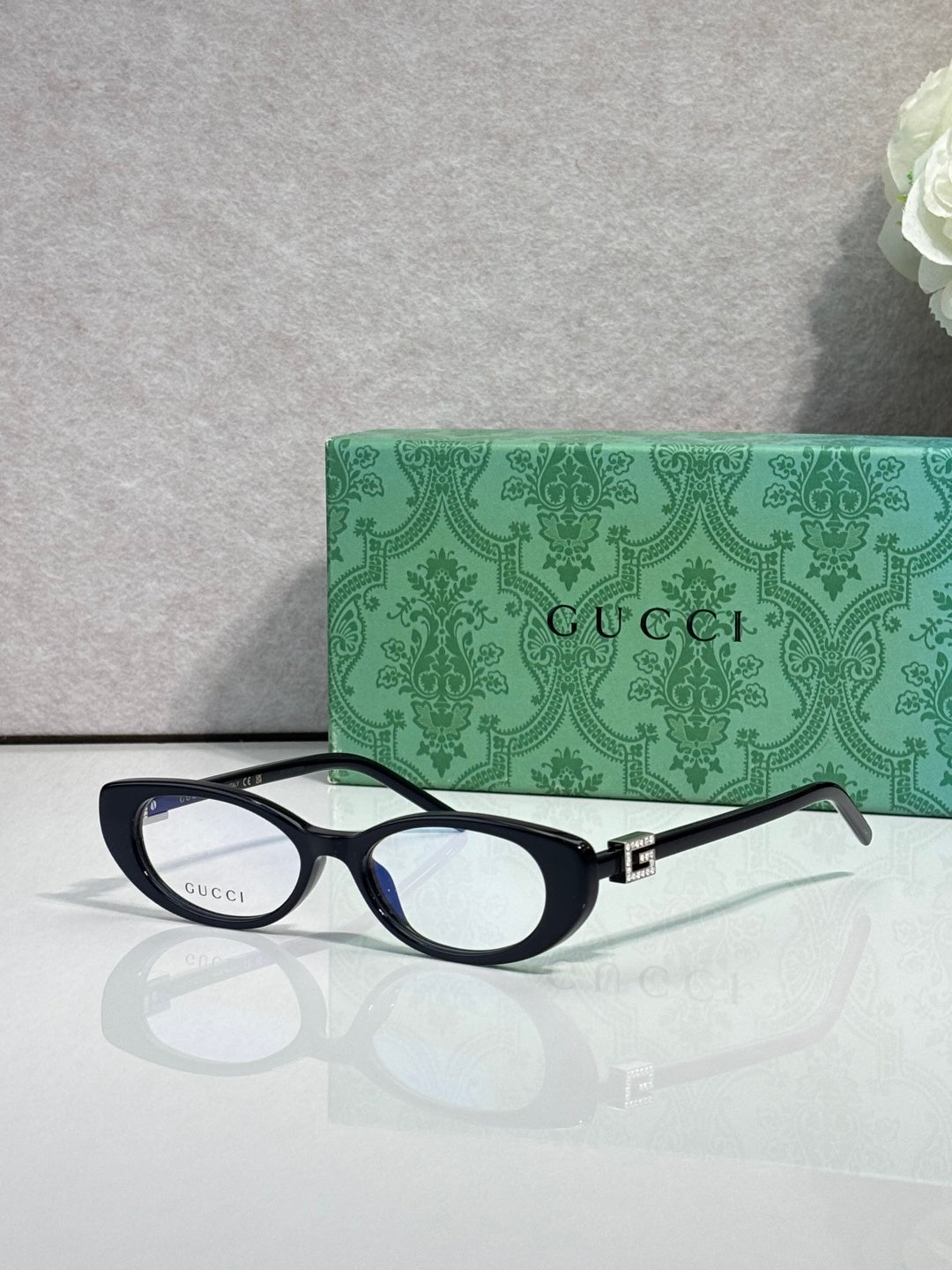 Cat-eye sunglasses with dark frames and clear lenses, gold logo hinge detail