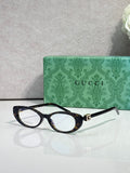 Cat-eye sunglasses with dark frames, clear lenses, and gold logo hinge