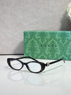 Cat-eye sunglasses with dark frames, clear lenses, and gold logo hinge