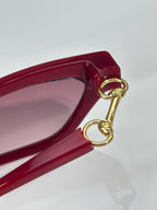 Red cat-eye glasses close-up with gold-tone hinge detail and pink lenses