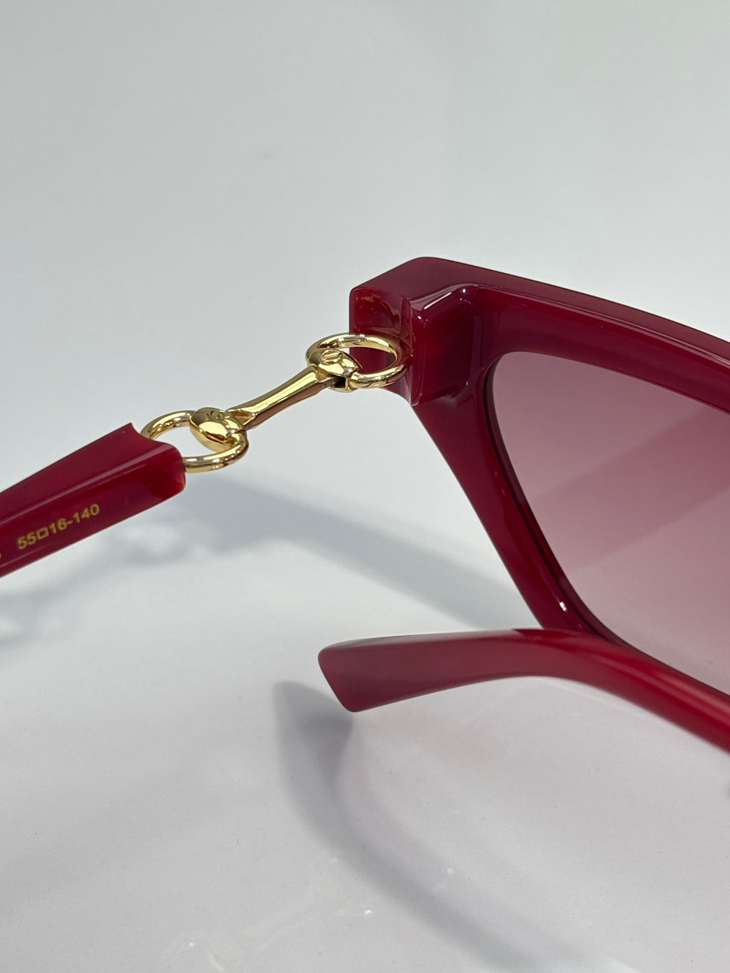 Red cat-eye glasses side view with gold-tone hinge hardware and pink lenses