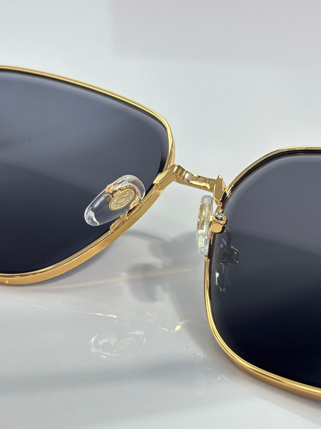 Cartier sunglasses detail: gold bridge and side hinge with dark lens