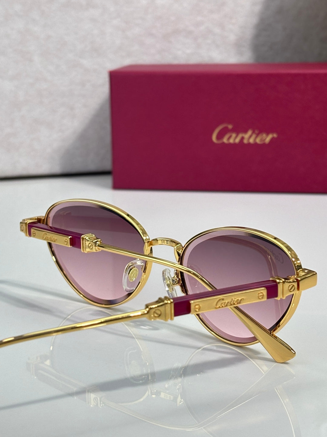 Gold-tone round sunglasses with pink lenses and temple emblem detail