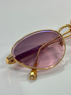 Gold-tone oval sunglasses with rose-pink lenses