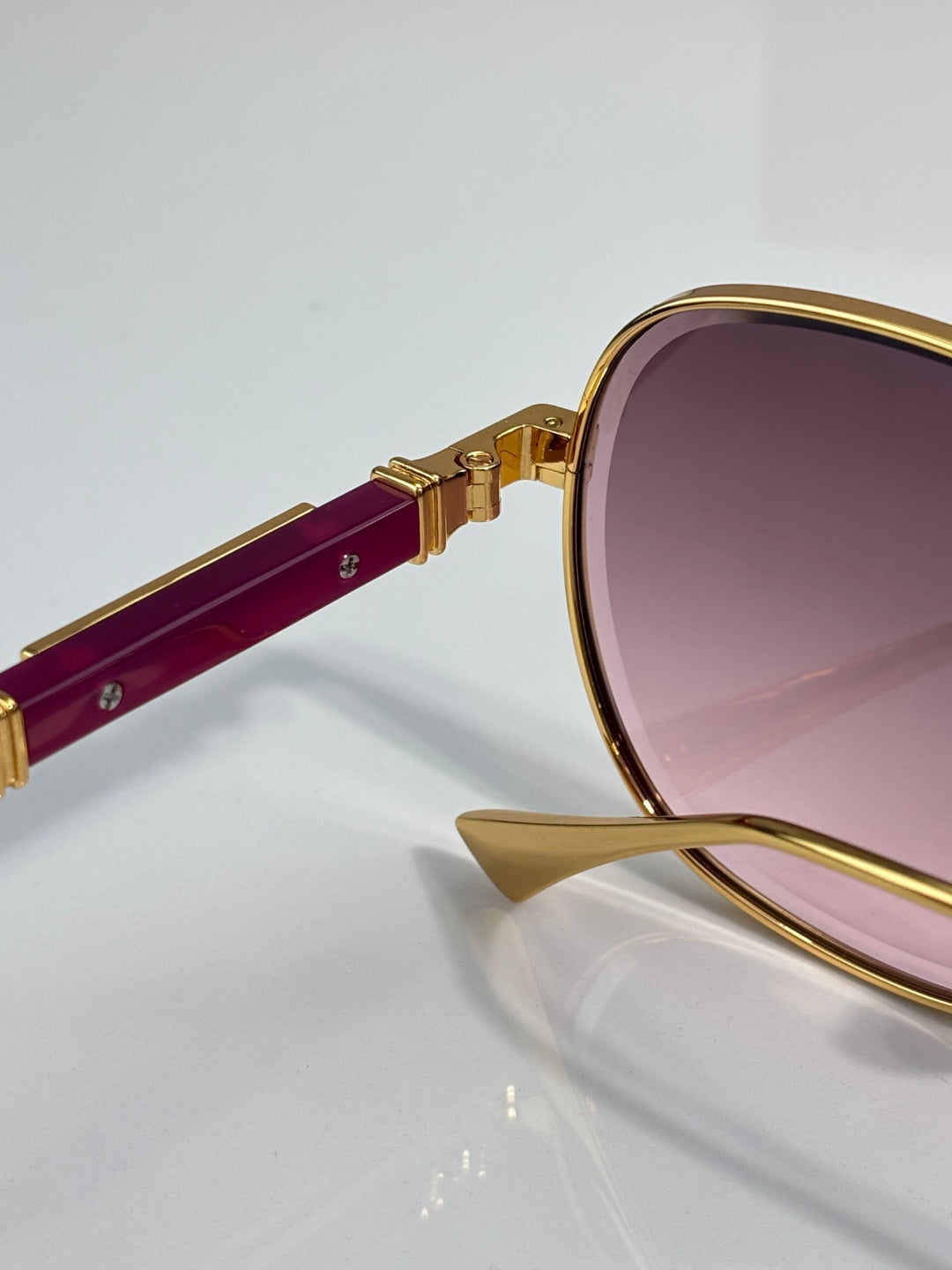 Round sunglasses with gold frame, burgundy temple, and purple-tinted lens