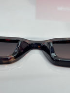 Prada sunglasses close-up: black frame bridge and curved dark lenses.