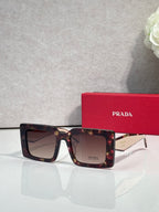 Prada sunglasses, tortoiseshell frames with dark lenses and Prada logo on lens.