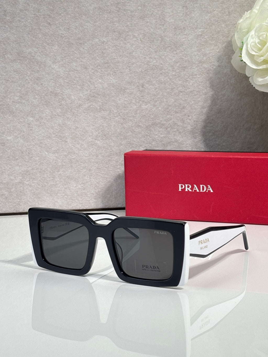 Prada sunglasses, black square frames with dark lenses and logoed arms.