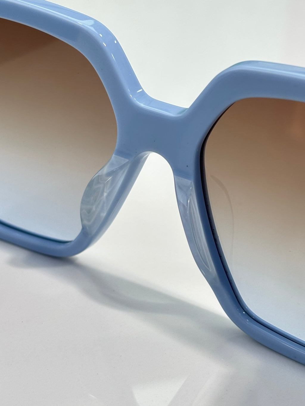 Light blue square sunglasses frame close-up with dark lens edge