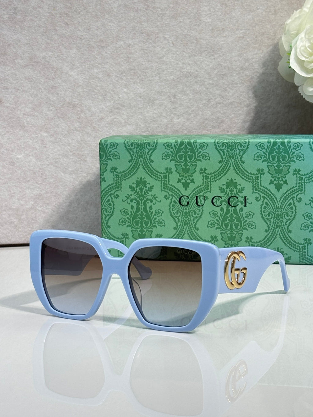 Gucci light blue square sunglasses with gold logo on temples and tinted lenses
