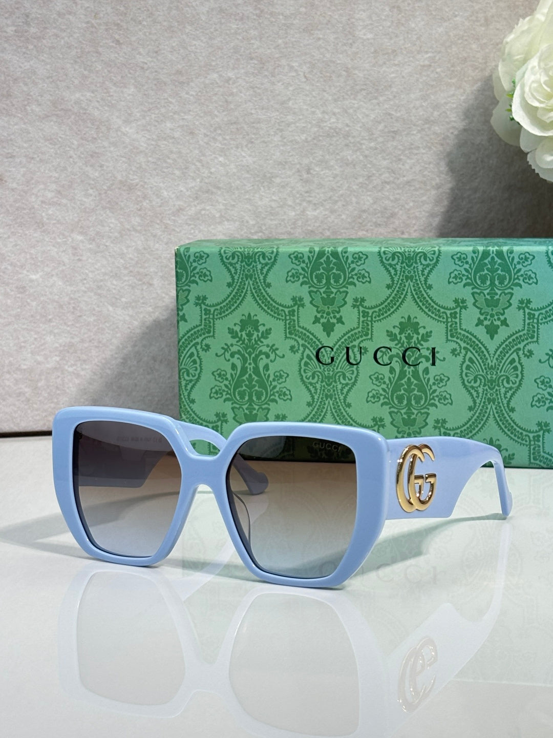 Gucci light blue square sunglasses with gold logo on temples and tinted lenses