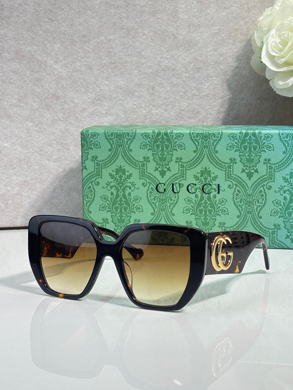 Gucci black square sunglasses with gold logo temple detail and warm gradient lenses