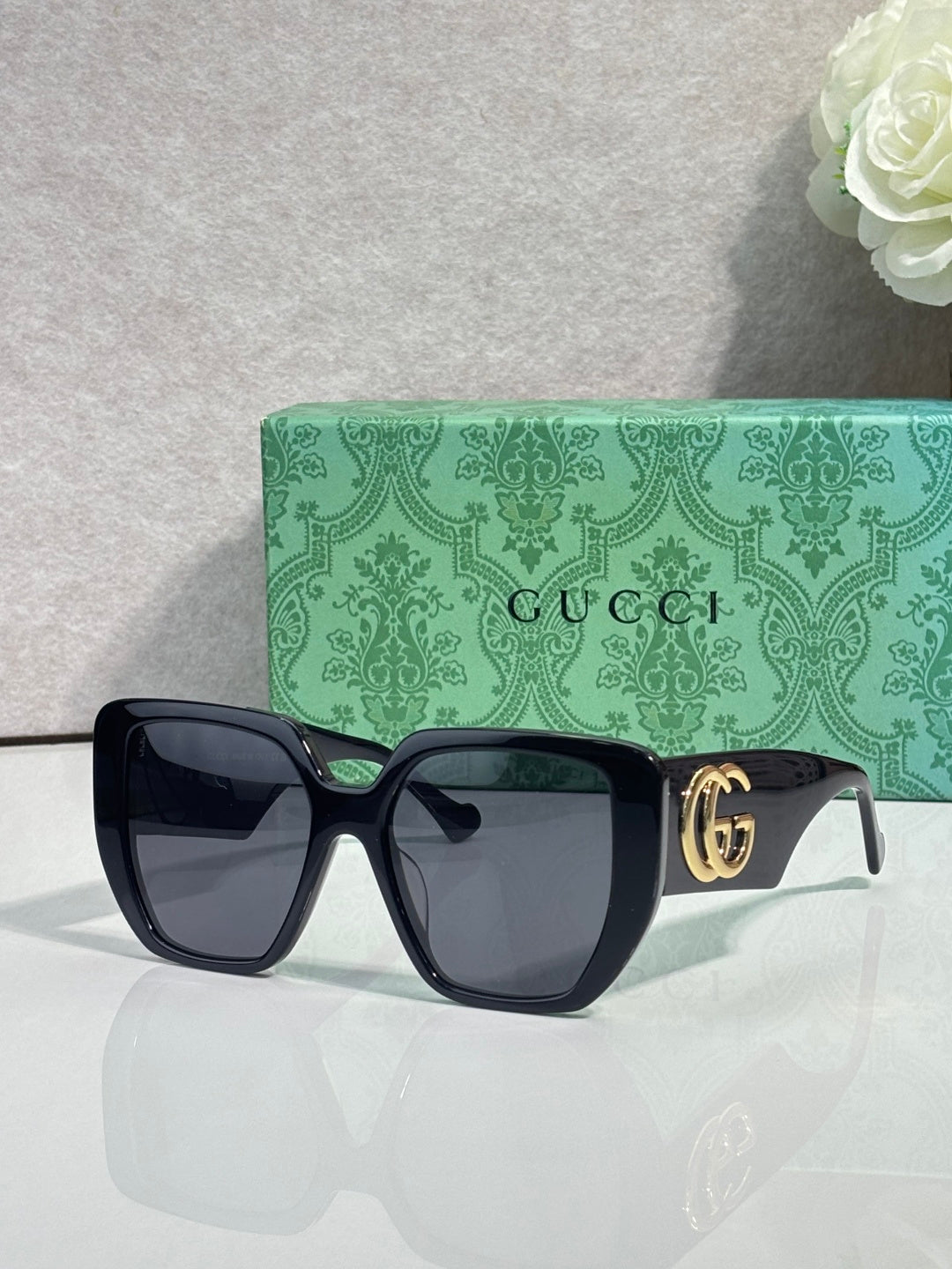 Gucci black square sunglasses with gold logo temple badge and dark-tinted lenses