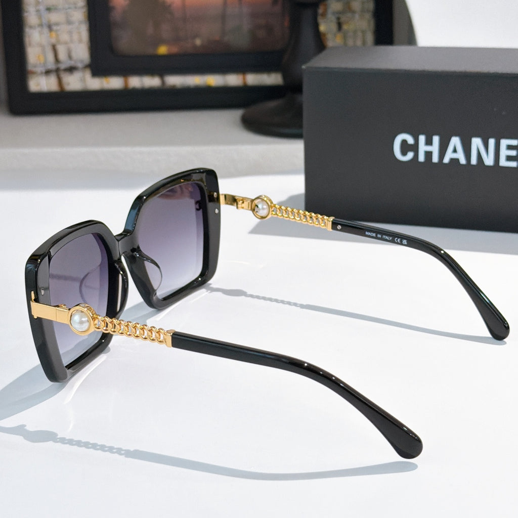 Black square sunglasses with purple lenses and gold chain temple accents