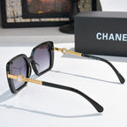 Black square sunglasses with purple lenses and gold chain temple accents