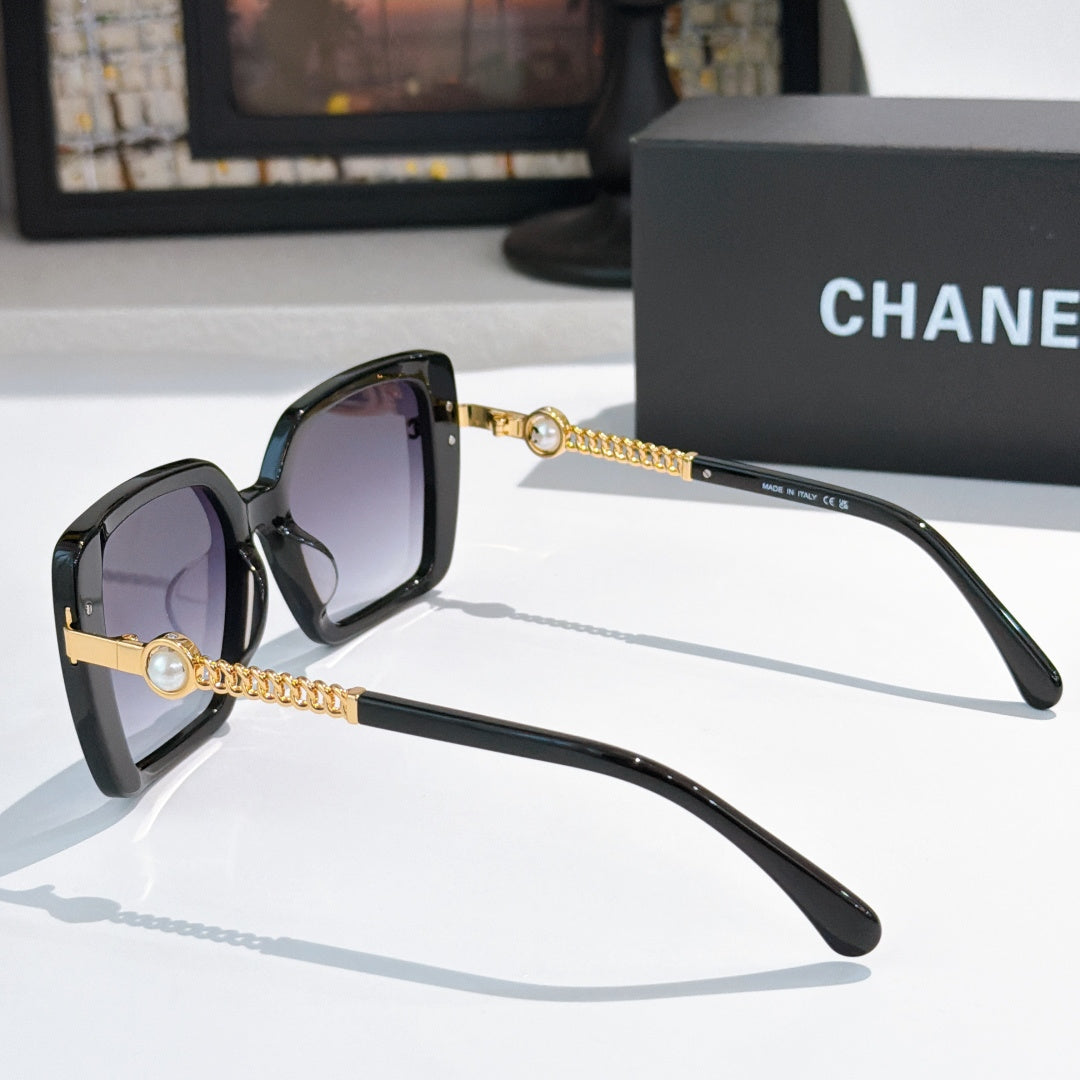 Black square sunglasses with purple lenses and gold chain temple accents