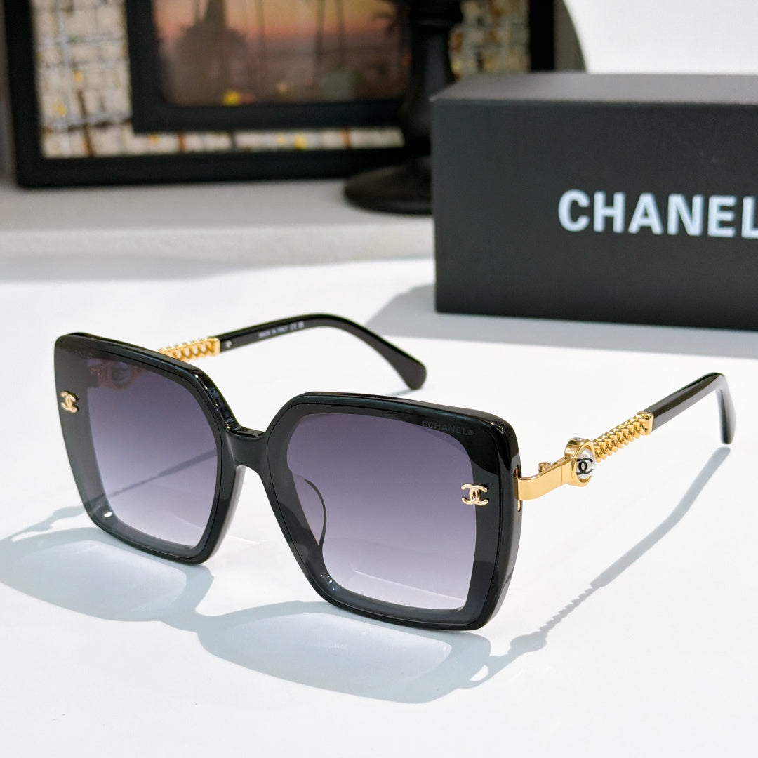 Black square sunglasses with purple lenses and gold chain temple details