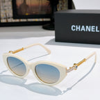 Ivory sunglasses with pale blue lenses and gold chain temples.